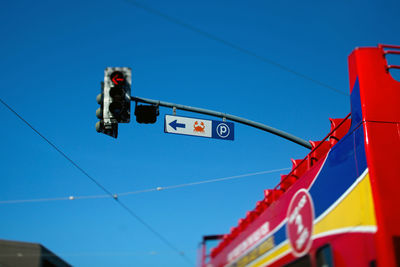 Low angle view of road signal and building against blue sky