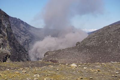 Smoke emitting from volcanic mountain against sky