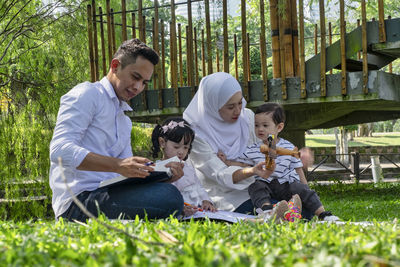 Father and son sitting on grassland