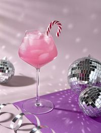 Pink cocktail with ice, mirror balls, new year vibes 