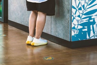 Low section of woman standing on tiled floor at home