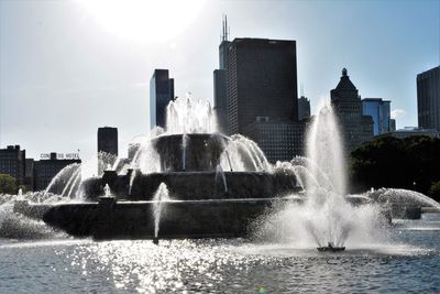 Water fountain in city against sky