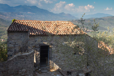 Old building by mountains against sky