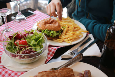 Midsection of woman having burger at table