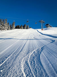 Three single traces at ski slope underneath a chairlift in the austrian alps against blue sky