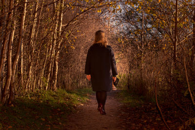 Rear view of woman standing in forest