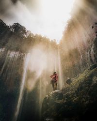 Man standing by trees in forest