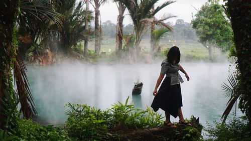 Rear view of woman standing on riverbank