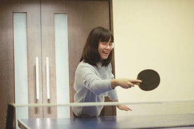 Young woman playing table tennis at home