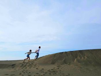 People on arid landscape against sky