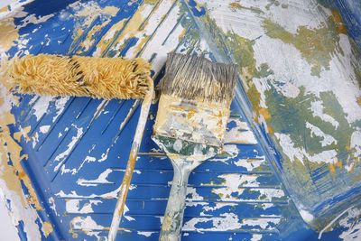 Directly above shot of paintbrushes and paint roller on tray 