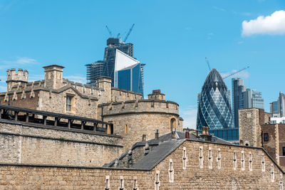 Detail of the tower of london on a sunny day with the modern skyscrapers of the city in the back