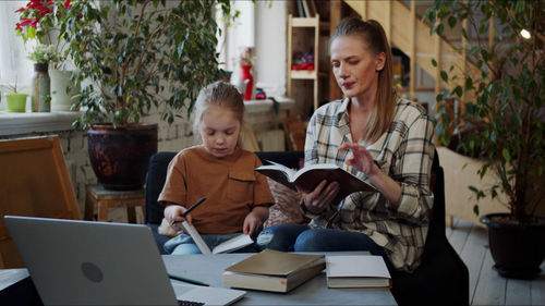 Mother and daughter reading book at home