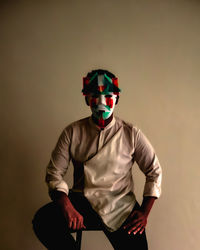 A man wears white mask covered with red and dark green geometric papers