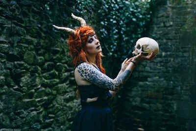 Woman with human skull standing in forest