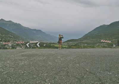 Rear view of woman photographing against sky