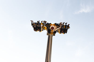 Low angle view of chain swing ride against sky