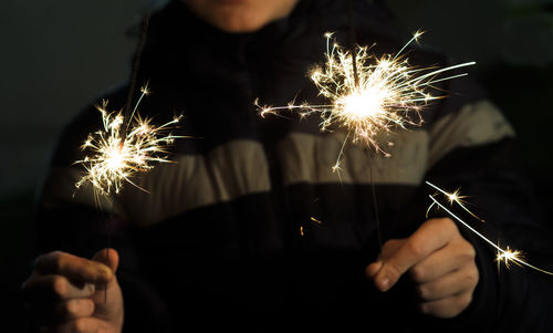 Midsection of child holding lit sparklers