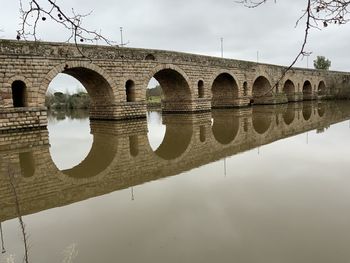Roman bridge reflected in river, upside down like an inversion of reality.