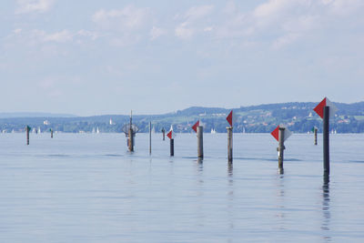 Wooden posts in sea against sky