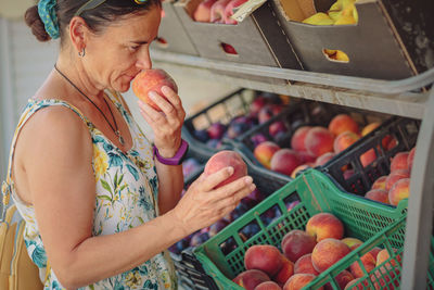 Mature woman choosing fruit in street store