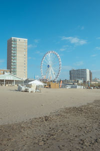 Ferris wheel on beach against buildings in city