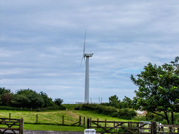 Trees on grassy field against cloudy sky