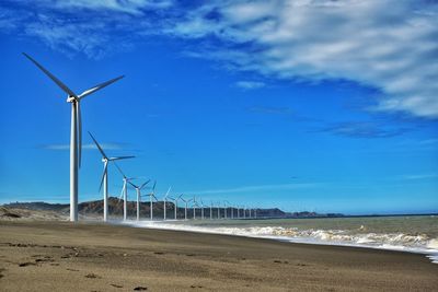 Wind turbines on beach against sky