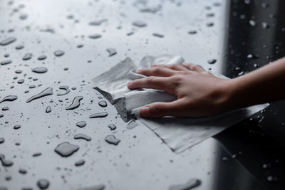 Close-up of hand touching wet paper on table