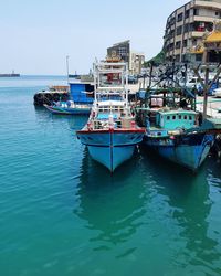 Moored boats in river against built structures