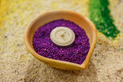 High angle view of candle and colored rice in diya during diwali