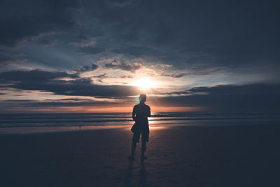 Rear view of man on beach during sunset