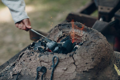 Close-up of blacksmith working at bonfire