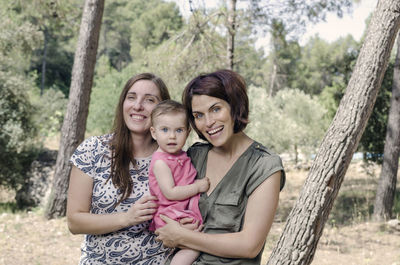 Portrait of happy friends against trees