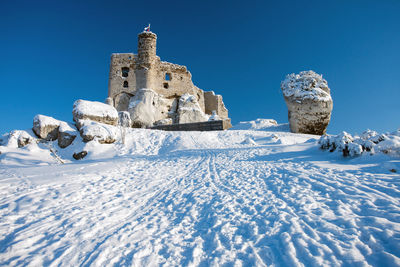 Low angle view of snow against clear blue sky