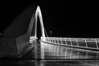 An illuminated walking bridge photographed during night time on a rainy day.