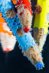 Close-up of colored pencils in water against black background