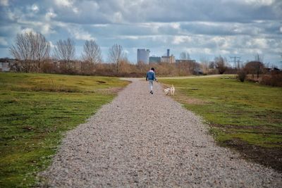 Rear view of man walking on land against sky