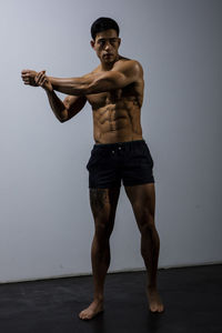 Shirtless muscular man exercising against wall