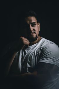 Portrait of young man against black background