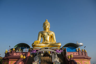 Low angle view of statue against building against clear sky