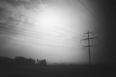 Electricity pylon against cloudy sky