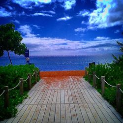 Pier on sea against cloudy sky