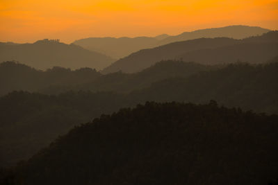 Scenic view of silhouette mountains against orange sky