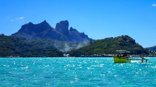 Scenic view of sea and mountains against clear blue sky