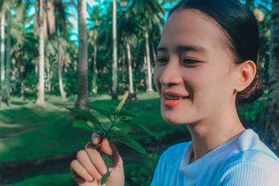 Close-up of young woman against trees