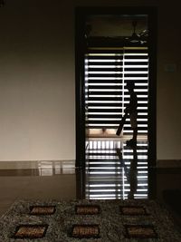 Rear view of woman standing on bed at home