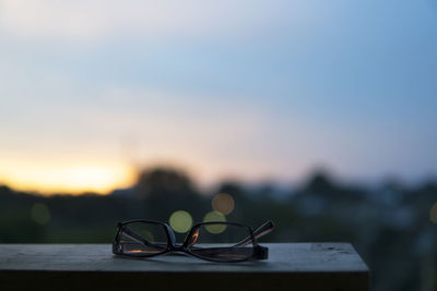 Close-up of sunglasses on table against sky during sunset