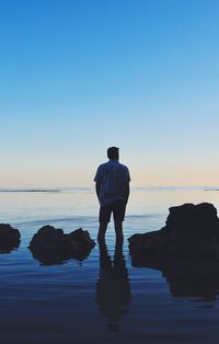 Rear view of silhouette man standing at beach