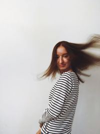 Portrait of smiling young woman standing against wall